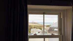 Una ventana con vistas a un paisaje costero, incluyendo casas y el mar.