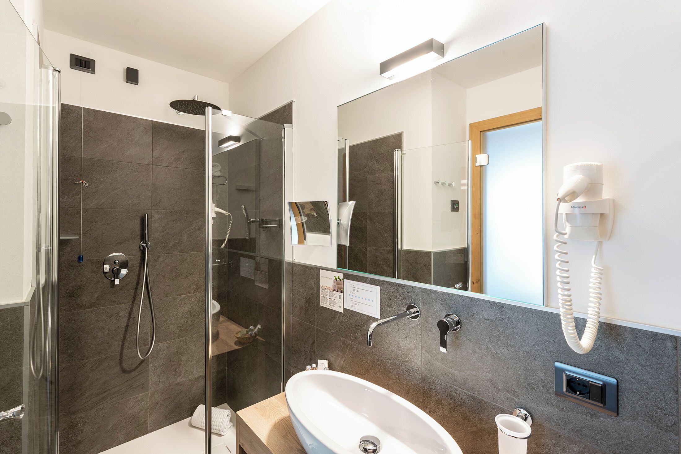 A modern bathroom with a glass-enclosed shower, a sink, and a mirror.