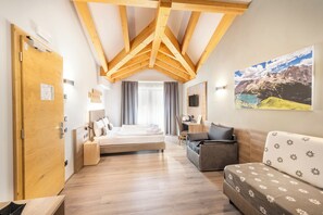 Een moderne hotelkamer met een houten plafond, een bed, een bank, een bureau en een groot raam met uitzicht op de bergen.