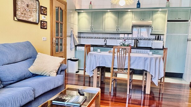Een woonkamer met een bank, salontafel en een eethoek met stoelen en een tafel.