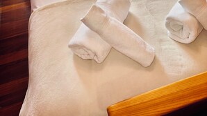 Een hotelkamer met twee bedden, elk voorzien van een witte spreidek en gebloemde kussens. Op de bedden liggen twee opgerolde handdoeken.
