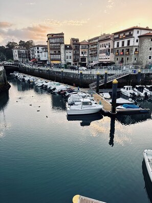 A marina with boats docked, a bridge, and buildings in the background.