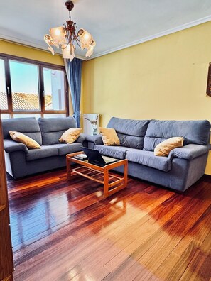 A living room with a grey sofa set, a wooden coffee table, and a chandelier.