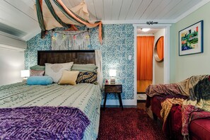 A bedroom with a large bed, a nightstand, a red rug, and a wall with a 'Welcome' sign.