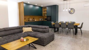 Ein modernes Wohnzimmer mit einem grauen Ecksofa, einem Holztisch und einem Essbereich mit Holztisch und Stühlen.