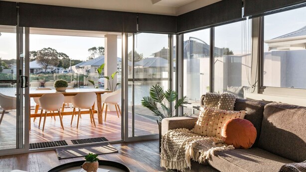Ein modernes Wohnzimmer mit einem großen Schiebeglasfenster, das auf eine Terrasse im Freien führt.