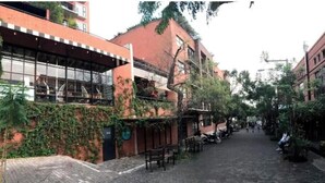 A narrow street lined with buildings, some with balconies and outdoor seating.