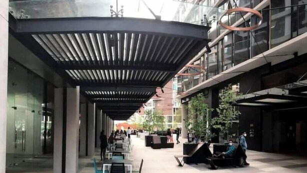 A covered outdoor area with seating and a person sitting on a bench.