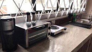 A kitchen counter with a coffee maker, a toaster, and a kettle.
