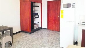 A room with a wardrobe, a microwave, and a small table.