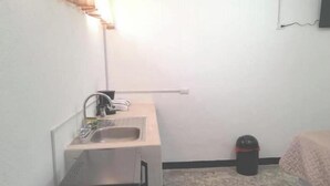 A small, compact room with a kitchenette area including a sink, a small refrigerator, and a trash bin. - 2 Nice and comfortable central apartment (Ciudad de Guatemala)