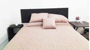 A neatly made bed with a black headboard and a light pink bedspread. - 2 Nice and comfortable central apartment (Ciudad de Guatemala)