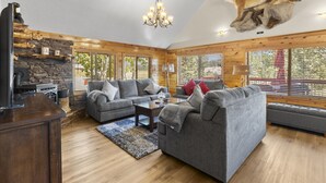 A cozy living room with a stone fireplace, wooden beams, and a mounted animal head.