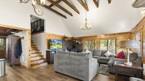 A spacious living room with a fireplace, a television, and a staircase leading to an upper level.