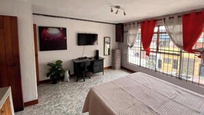 A bedroom with a bed, a desk, a chair, a TV, and a window with curtains. - 4 Stunning Cool Studio in tourist area (Ciudad de Guatemala)
