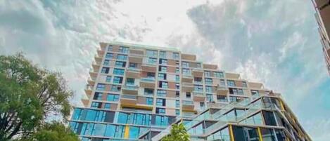 Un edificio de varios pisos con un diseño arquitectónico moderno, que combina fachadas de vidrio y hormigón.