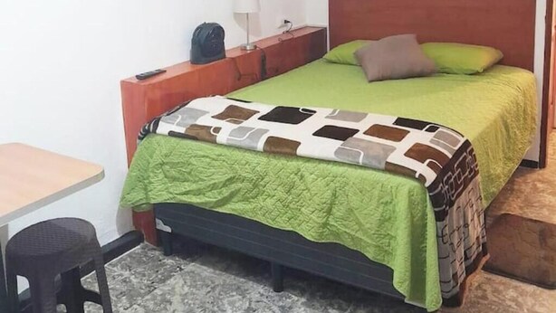 A small, neatly arranged bedroom with a single bed, a bedside table, a lamp, and a chair. - 7 Cool studio at the best zone (Ciudad de Guatemala)