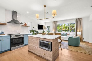 Una cocina moderna con horno empotrado, microondas y una isla central con fregadero.
