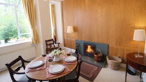 A dining room with a fireplace, a table set for four, and a view of the outdoors. - Old Belfield, Bowness-on-Windermere with lake view (Bowness-on-Windermere)