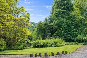 A lush garden with a variety of trees and shrubs, a well-maintained lawn, and a gravel path.