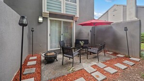 An outdoor patio with a fire pit, seating, and a red umbrella. - 2 Lux King Beds - Short Walk to Truist Park (Smyrna)