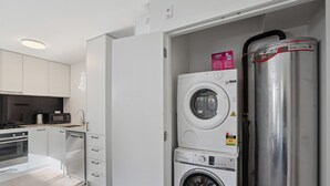 A compact kitchen with white cabinets, a microwave, and a kettle. - Morepork Retreat - 1BDRM & Central (Queenstown)