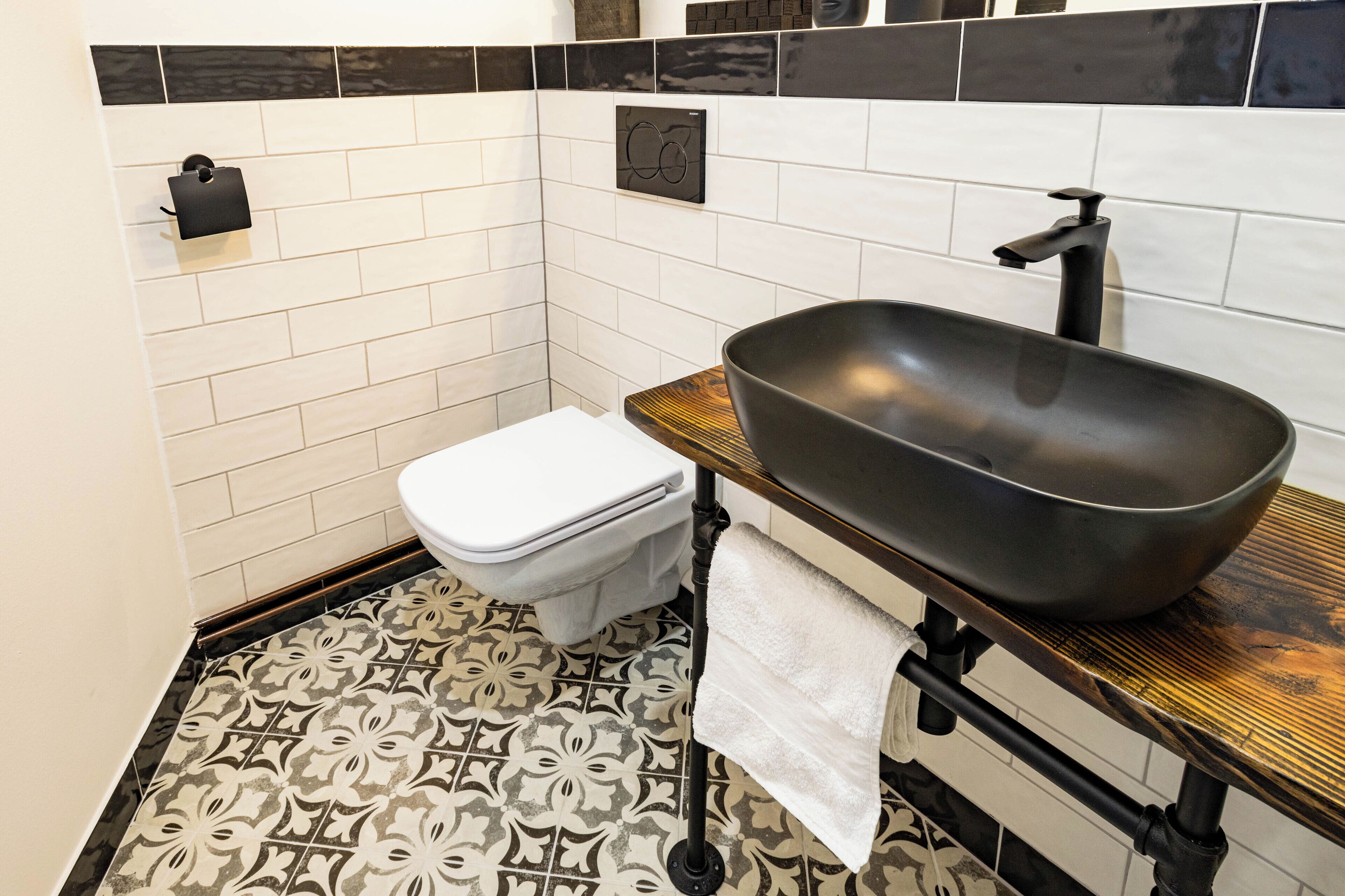 Et badeværelse med toilet, håndvask og gulvfliser med mønster.
