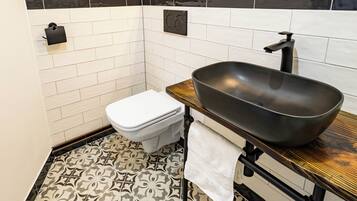 Et badeværelse med toilet, håndvask og gulvfliser med mønster.
