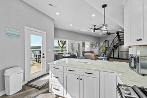 A modern kitchen with white cabinets, a marble countertop, and a built-in oven.