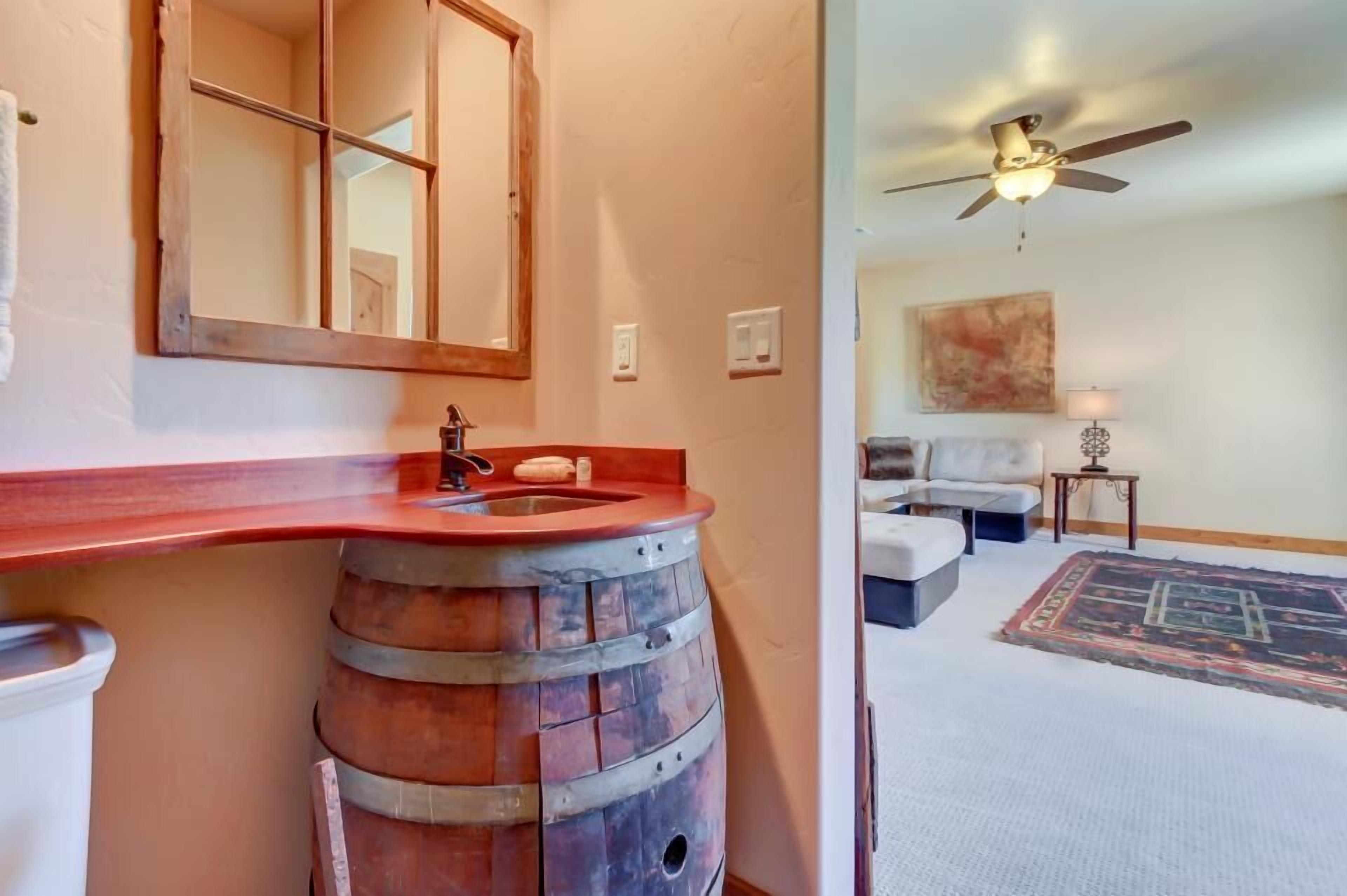 Un baño con un lavabo de barril de madera y un espejo.