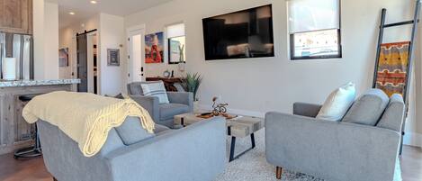 A modern living room with two grey sofas, a coffee table, and a white rug.