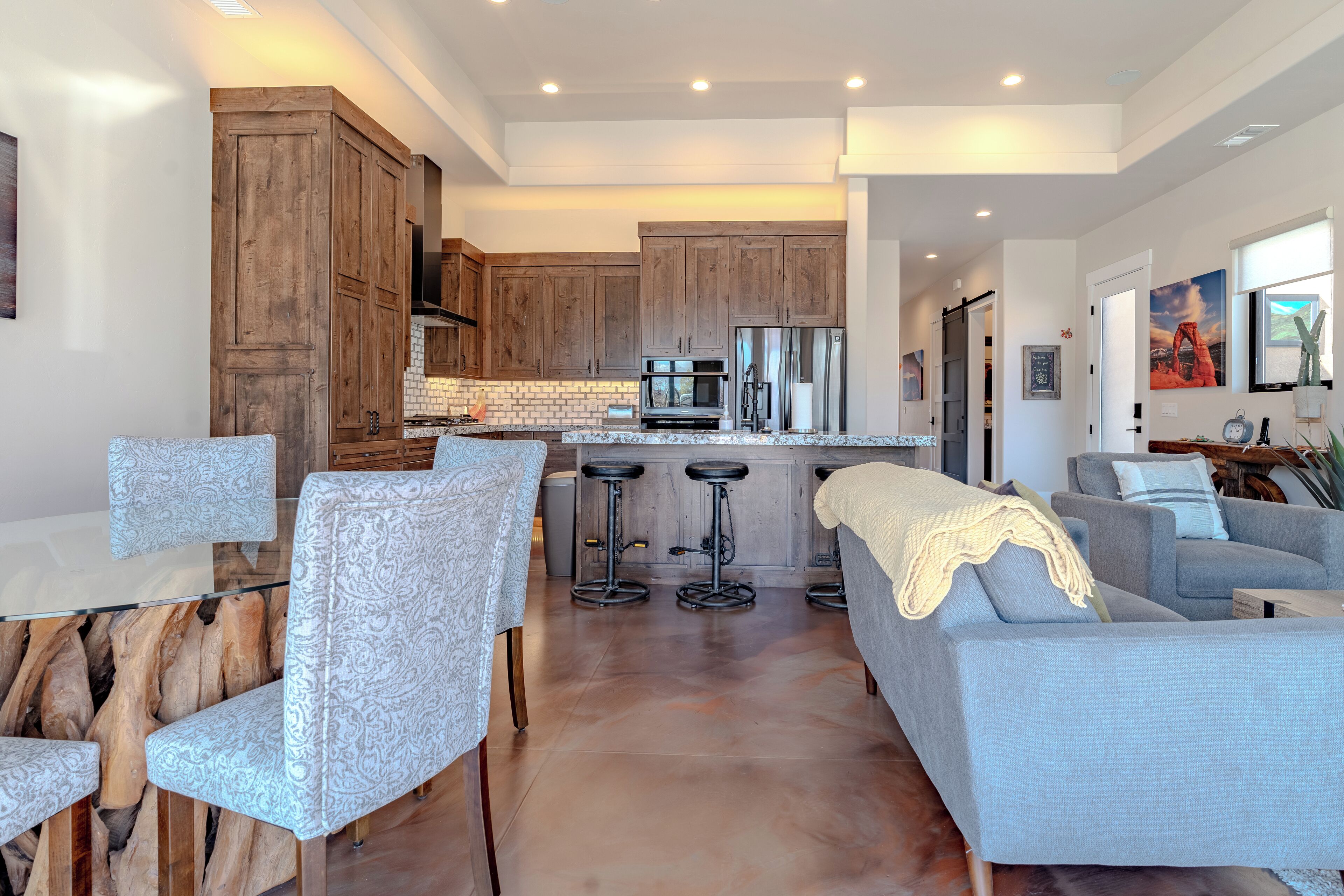 A modern kitchen with wooden cabinets, a central island, and bar stools.