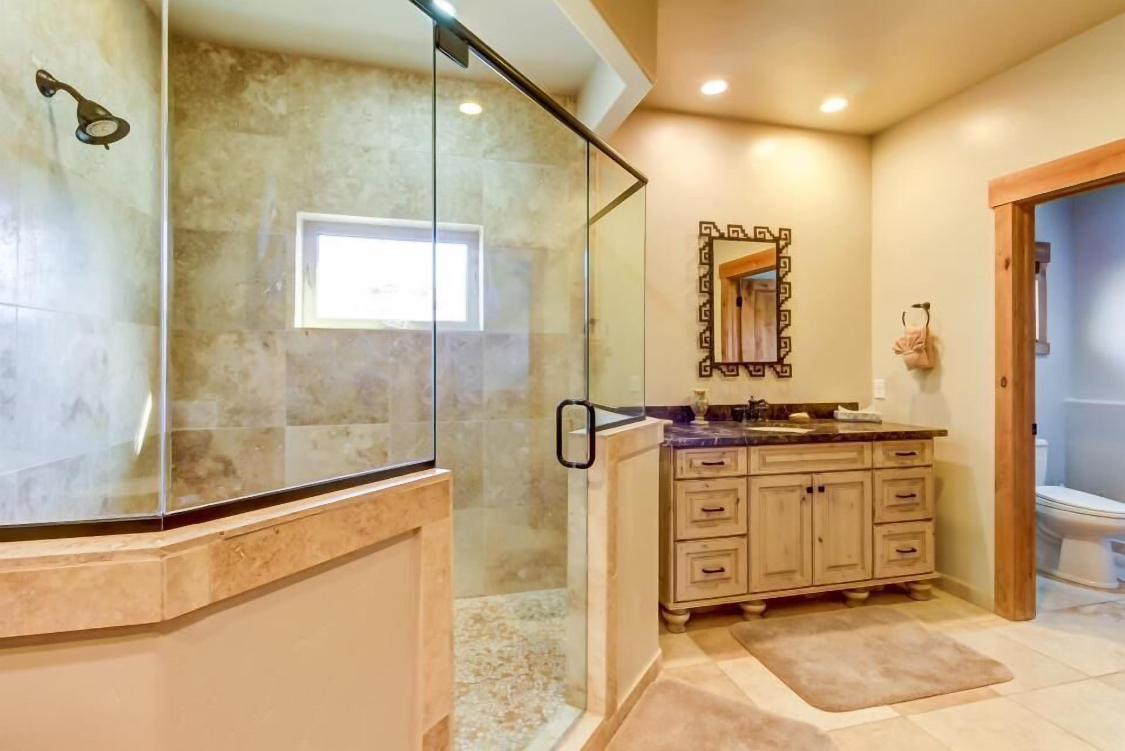 A bathroom with a glass-enclosed shower, a vanity with a mirror, and a toilet.
