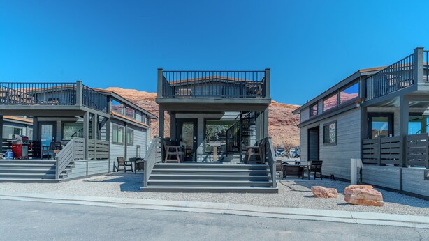 A modern building with a central entrance, two balconies, and a gravel driveway. - Village Camp Moab (Moab)
