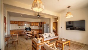 A spacious living area with a sofa set, wooden furniture, and a kitchen in the background. - Pacífico Surf  (Puerto Escondido)