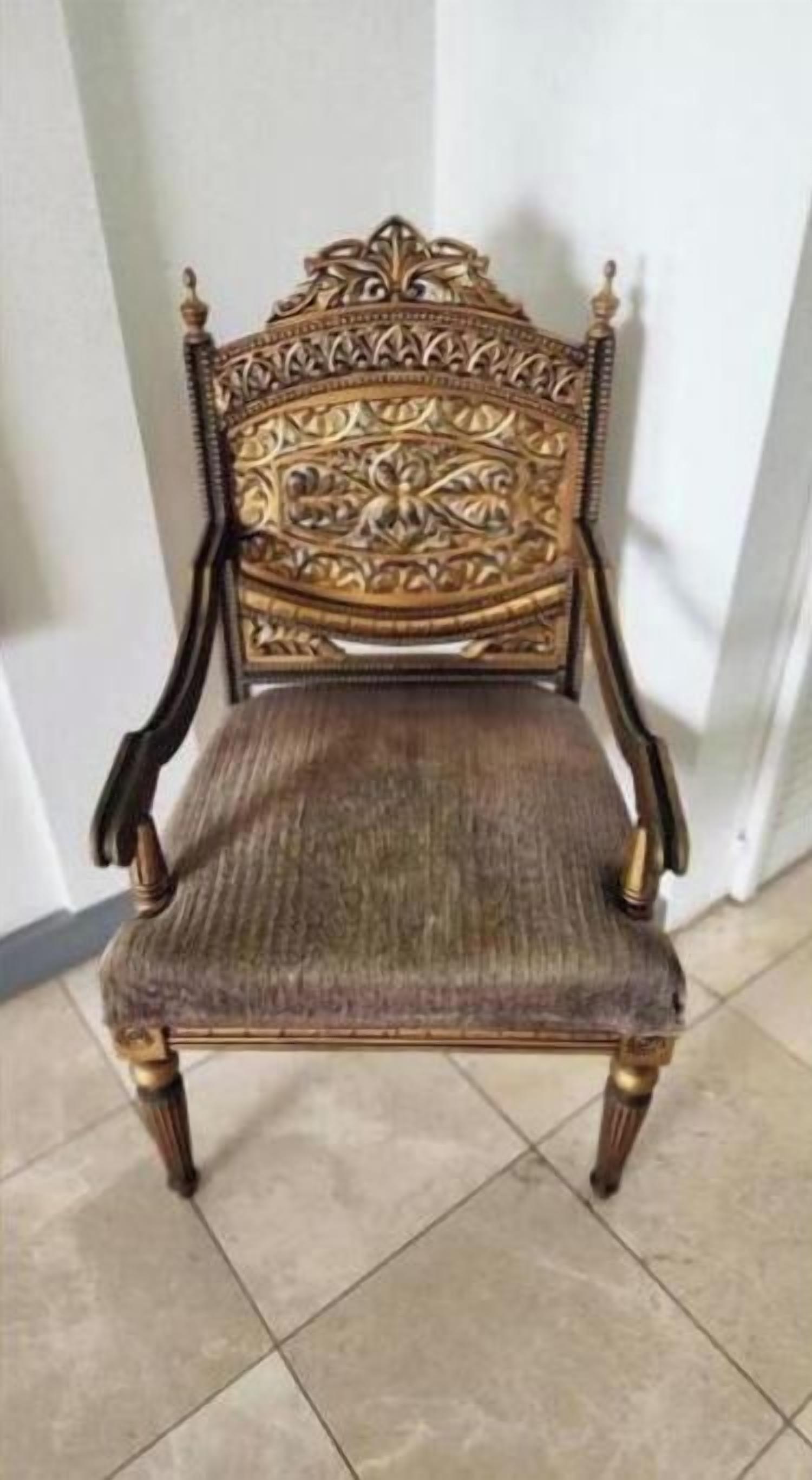 A wooden chair with intricate carvings and a cushioned seat.