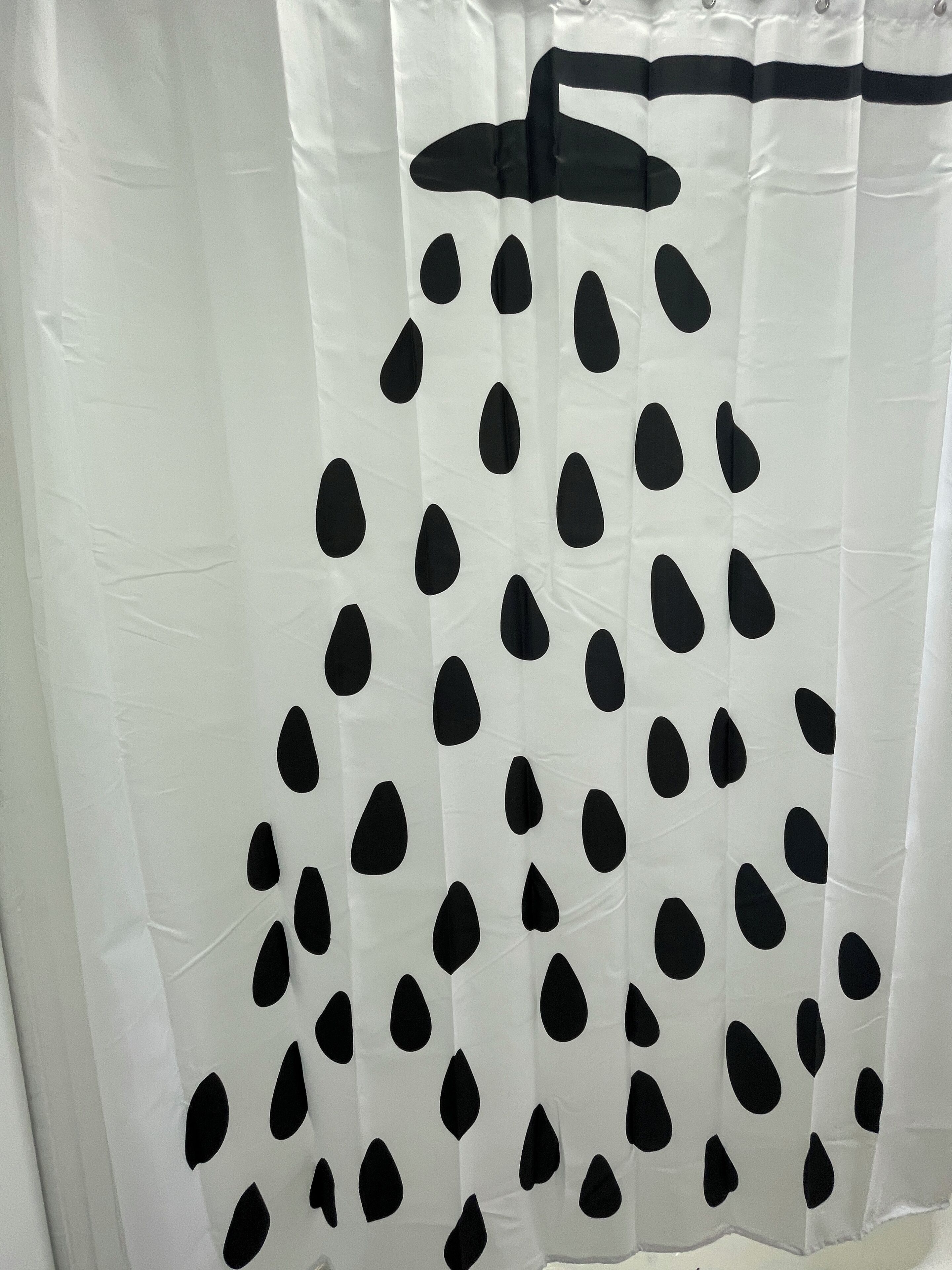 A white curtain with black teardrop patterns.