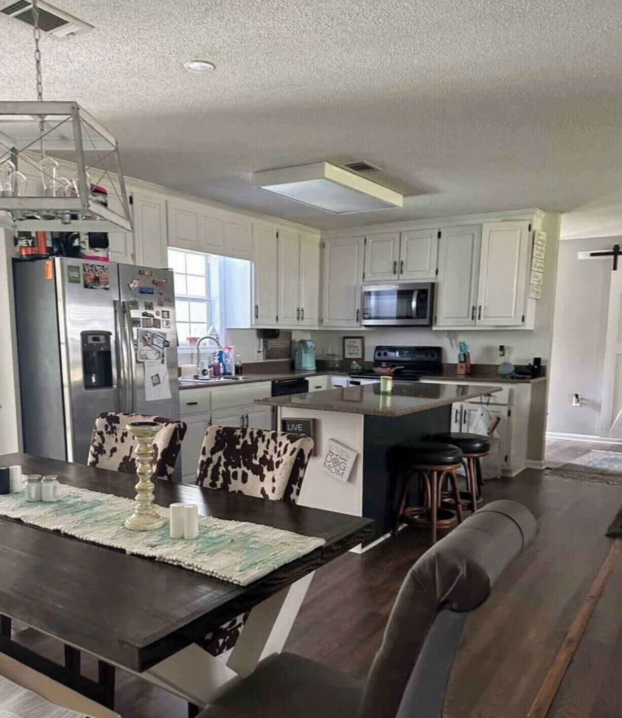 A modern kitchen with white cabinets, stainless steel appliances, and a central island with bar stools.