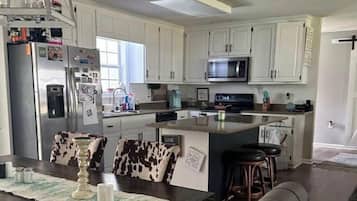 A modern kitchen with white cabinets, stainless steel appliances, and a central island with bar stools.