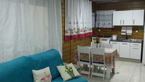 Una sala de estar con un sofá azul, una mesa de comedor con sillas y una zona de cocina con armarios y una estufa.