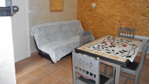 Una stanza con una parete in legno, un divano, un tavolo con tovaglia fantasia e una sedia.