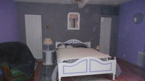 Una camera da letto con un letto, una sedia, un comodino e uno specchio.