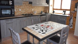 Una cucina con mobili grigi, un forno a microonde, un fornello e un tavolo da pranzo con sedie.