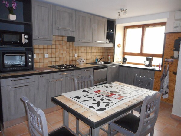 Una cocina con gabinetes grises, un microondas, una estufa y una mesa de comedor con sillas.