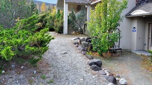 A gravel driveway leading to a building with a covered porch and a door marked "5005". - Wake Up to Ski Runs, Wind Down by the Fire (Carrabassett Valley)