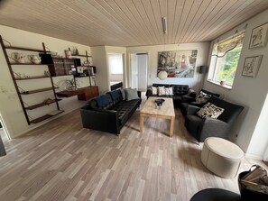 Ein Wohnzimmer mit einer schwarzen Couch, einem Holztisch und einem Bücherregal.