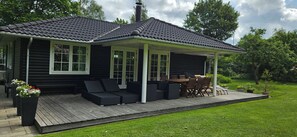 Eine Blockhütte mit überdachter Veranda, Sitzgelegenheiten im Freien und einem Garten.