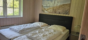 Ein Zimmer mit Bett, Fenster und einem Strandbild.