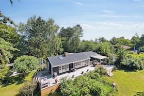 A modern house with a large deck, a covered patio, and a well-maintained garden.