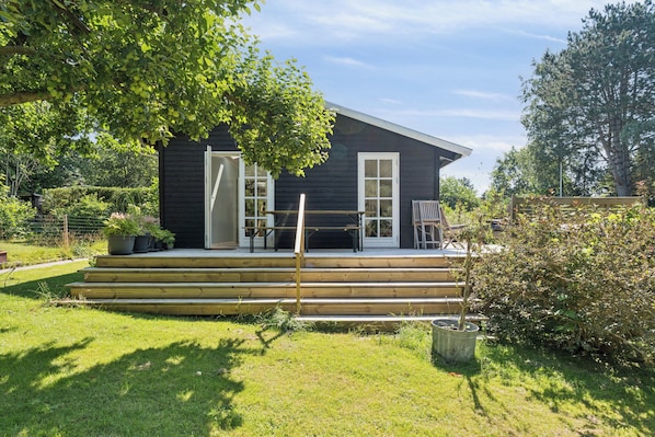 Ein dunkles Holzhaus mit Veranda, Treppe und Blumentöpfen.